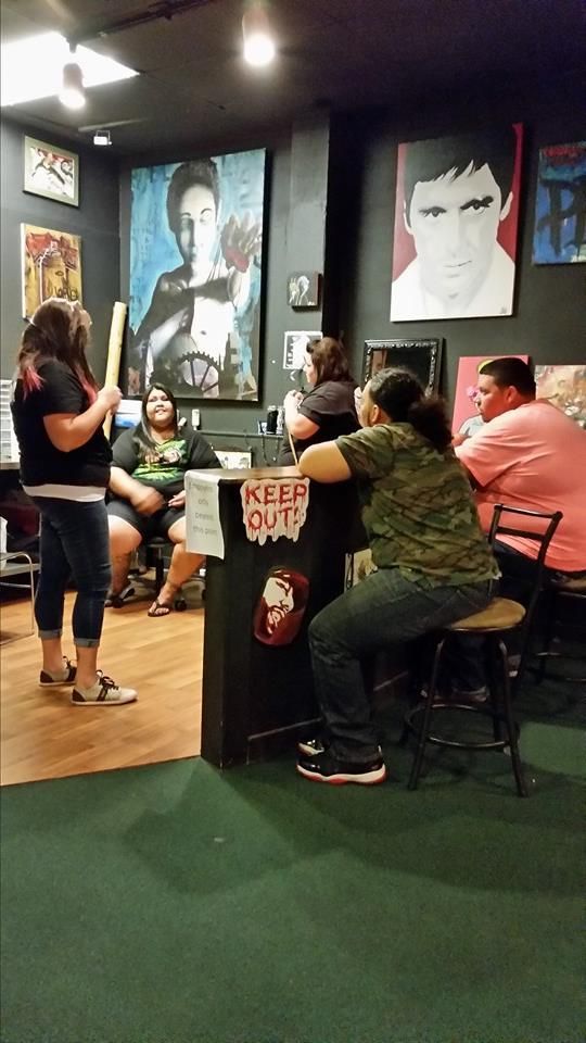 People gathered in a room with artwork on the walls; one person holds a bat.