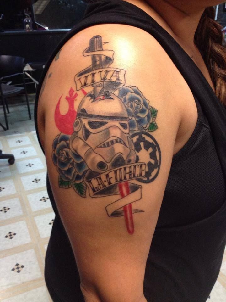Star Wars themed tattoo on arm. Features a Stormtrooper helmet, Rebel Alliance symbol, and roses.