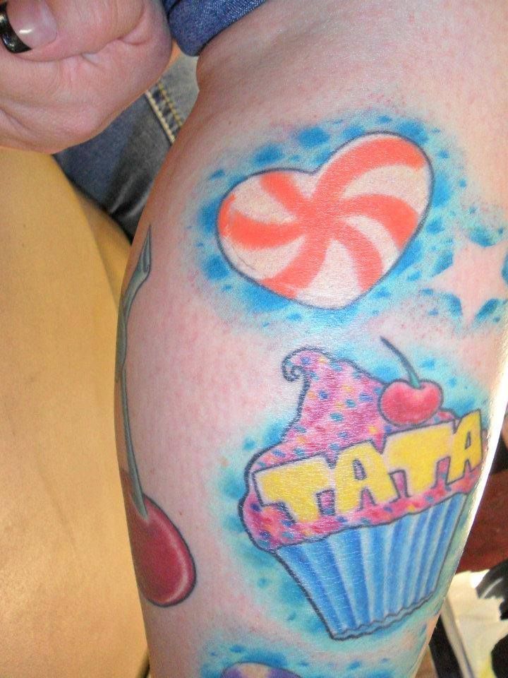 Colorful leg tattoo featuring a swirled heart, cupcake with 
