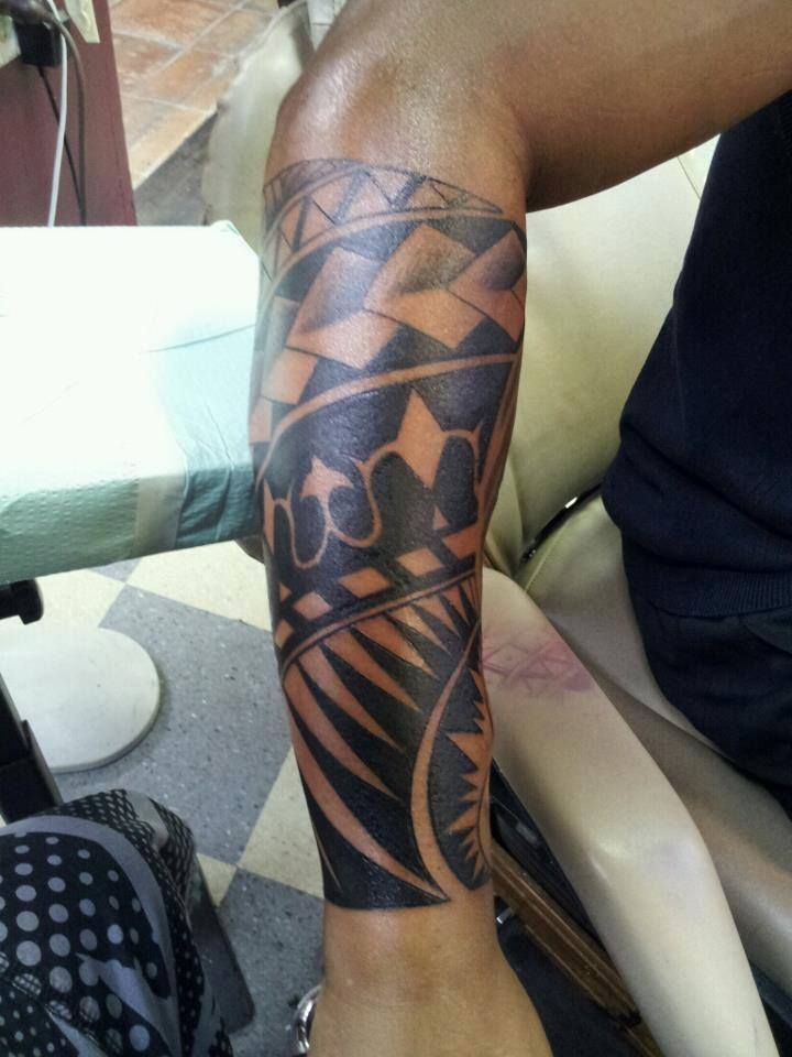 Tattoo on arm, black tribal patterns with brown accents, forearm in focus.