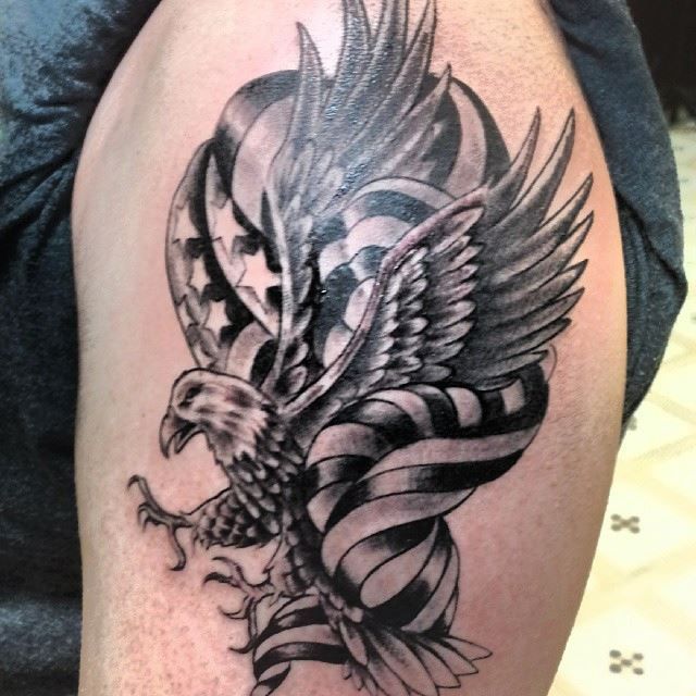 Tattoo of an eagle with outstretched wings and American flag details on an arm.