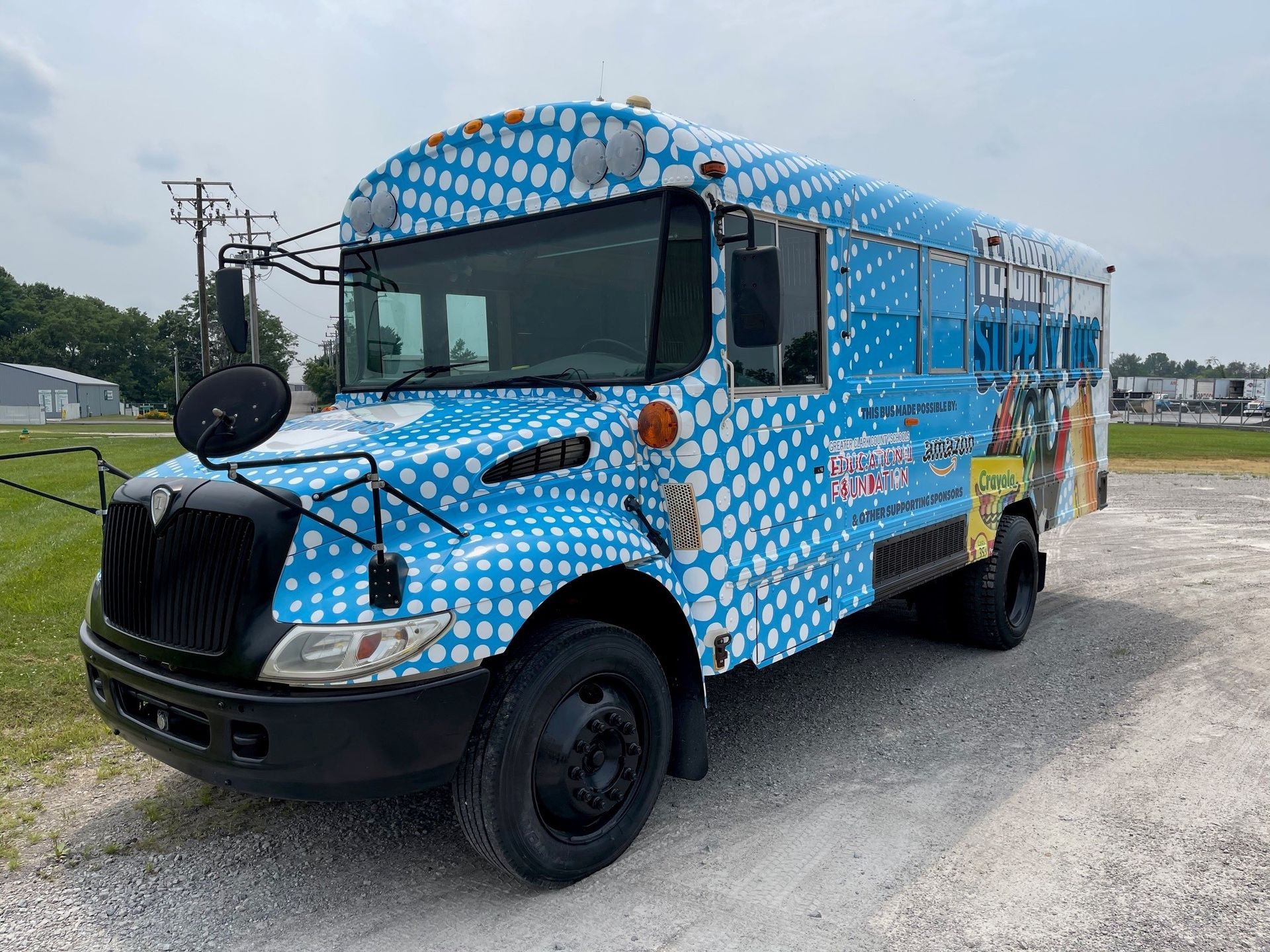 A blue school bus is parked in a gravel lot.