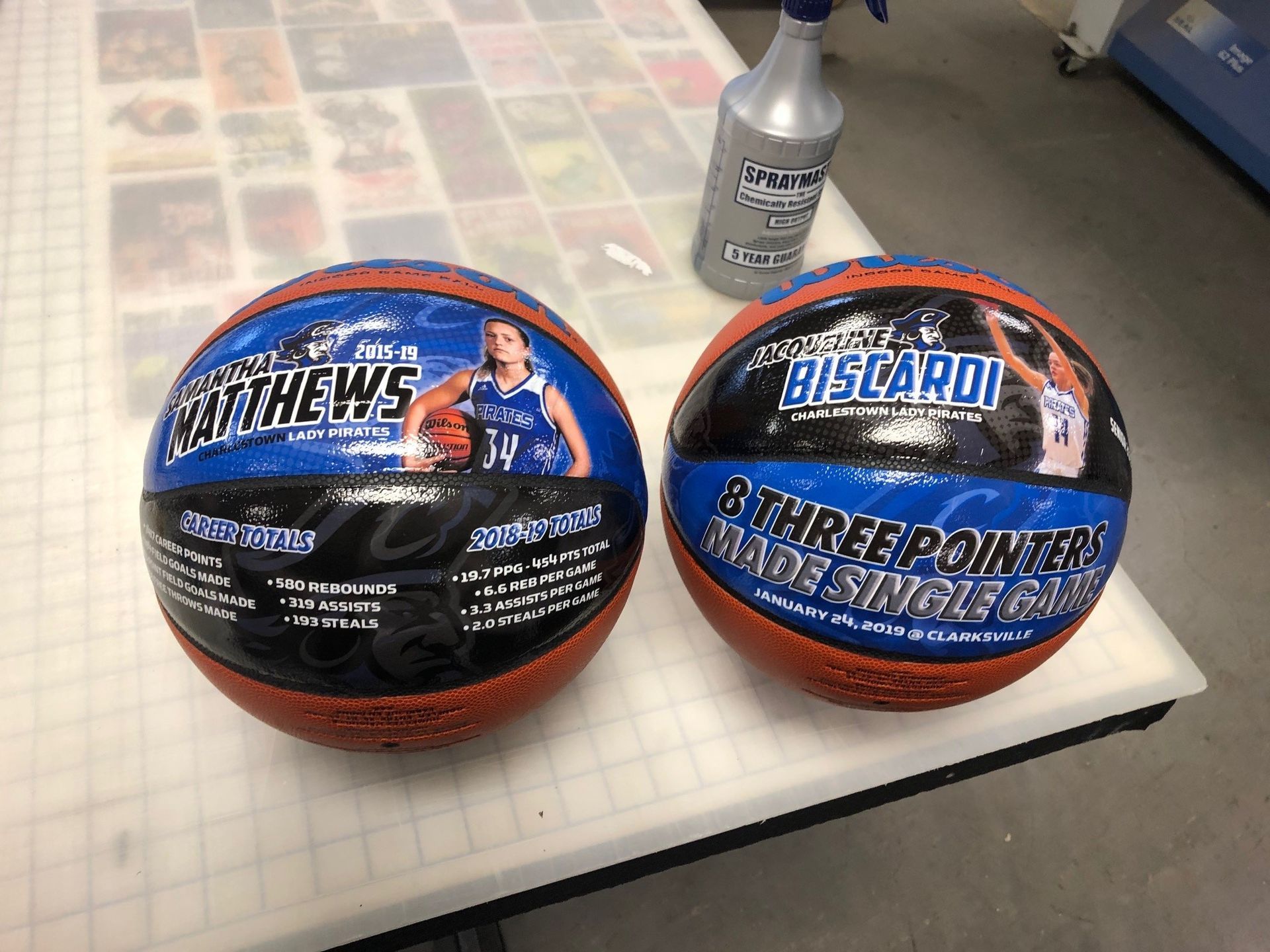 Two basketballs are sitting on a table next to a spray bottle.