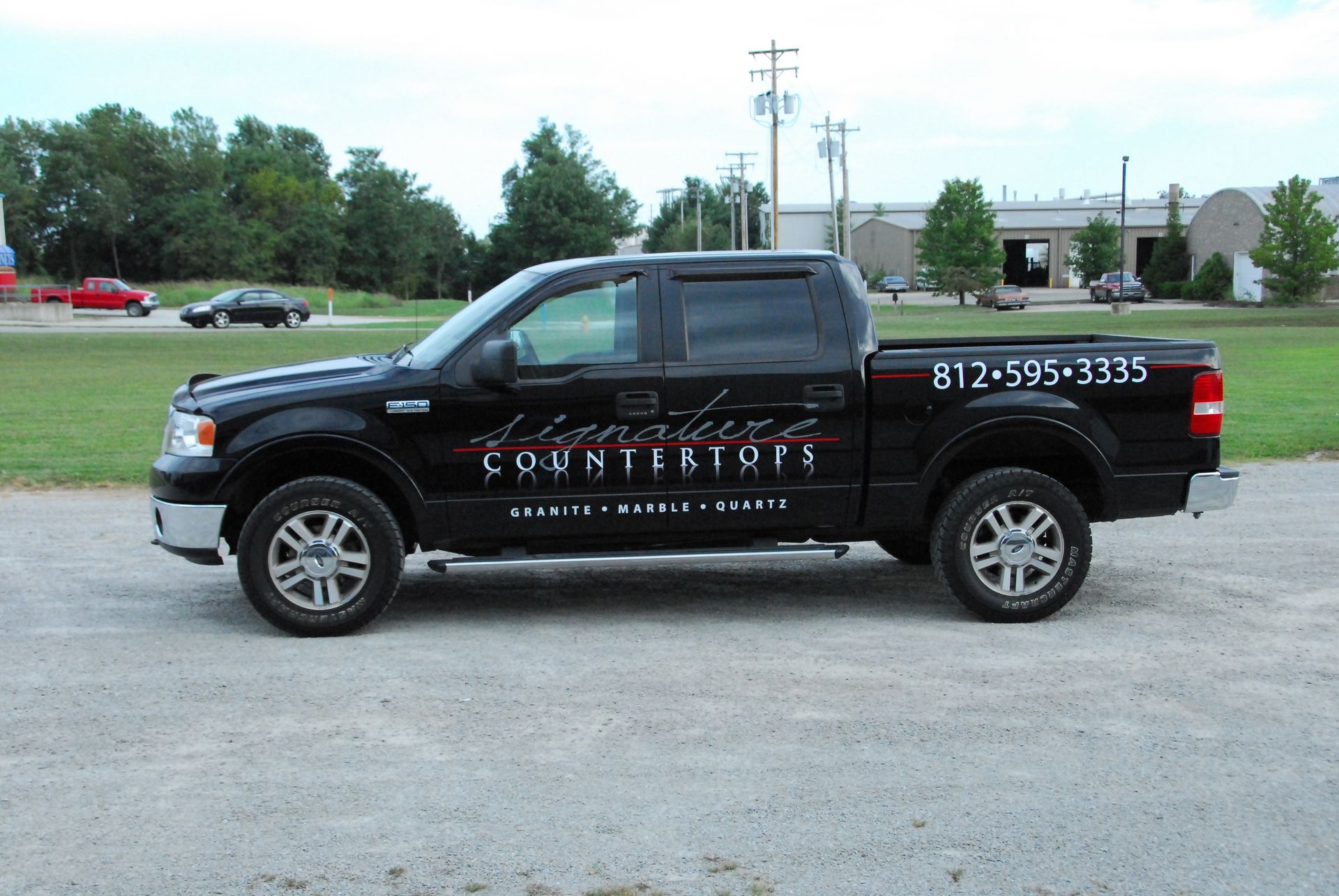 A black truck is parked in a gravel lot