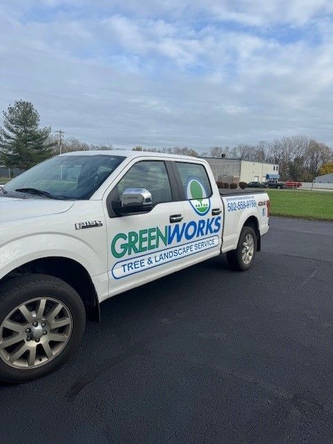 A white truck with greenworks written on the side is parked in a parking lot.