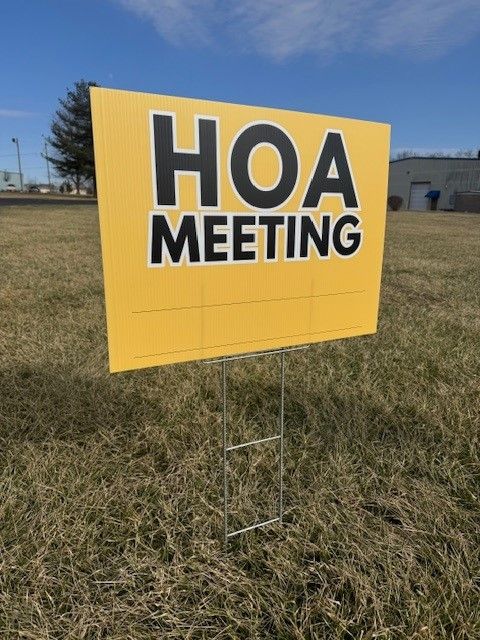 A yellow sign that says hoa meeting on it