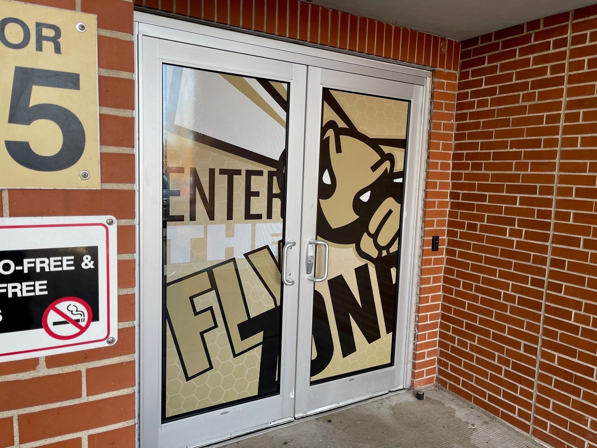 A brick building with a glass door that says enter fly on it