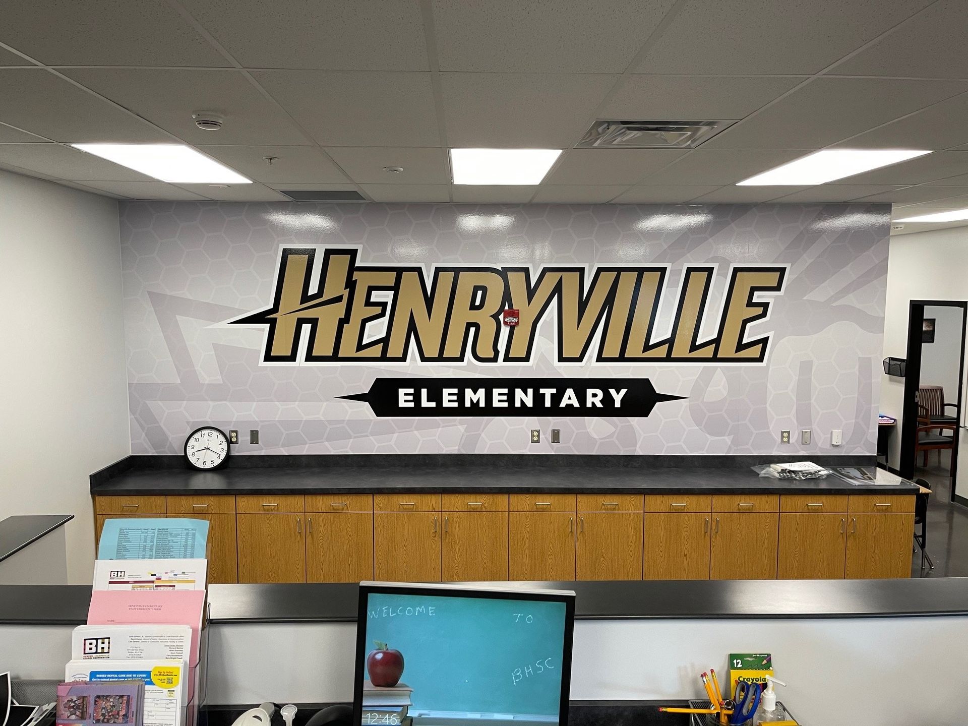 A sign for henryville elementary is on the wall above a desk.