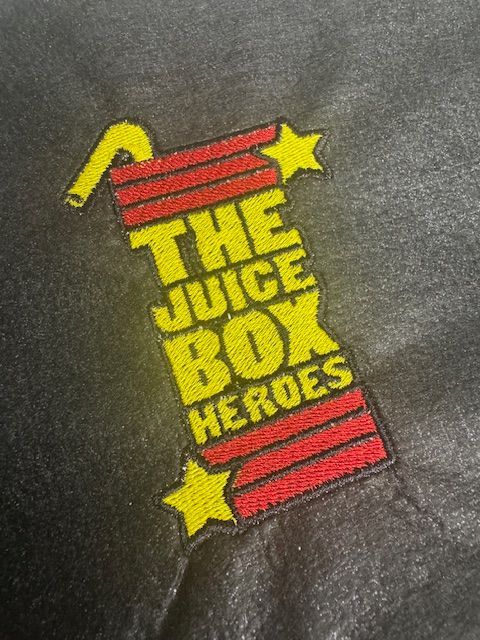 The juice box heroes logo is embroidered on a black shirt