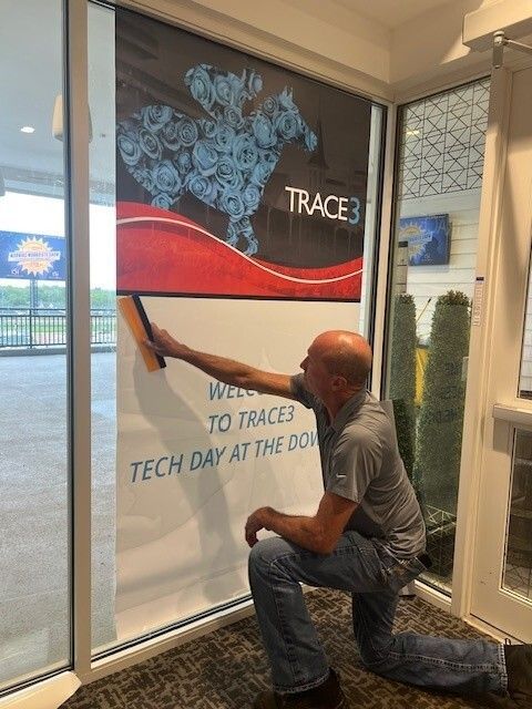A man is kneeling down and cleaning a window with a wiper.
