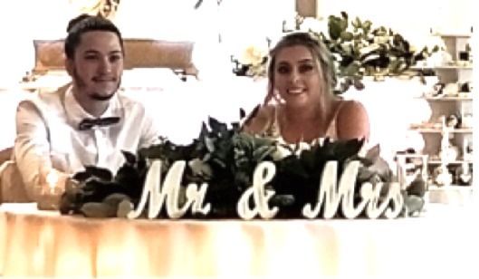 A bride and groom are sitting at a table with a mr. and mrs. sign.