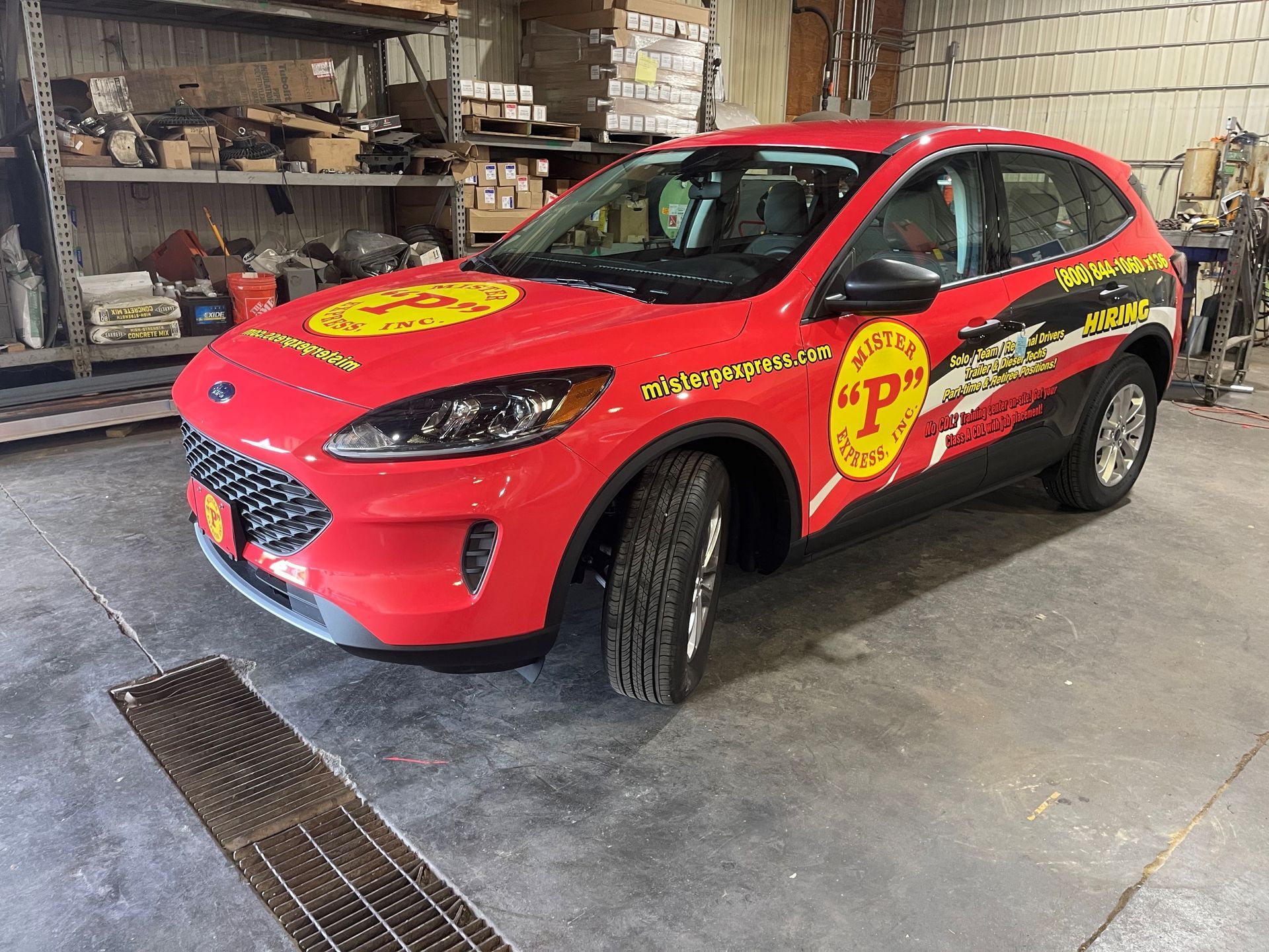 A red ford escape is parked in a garage.