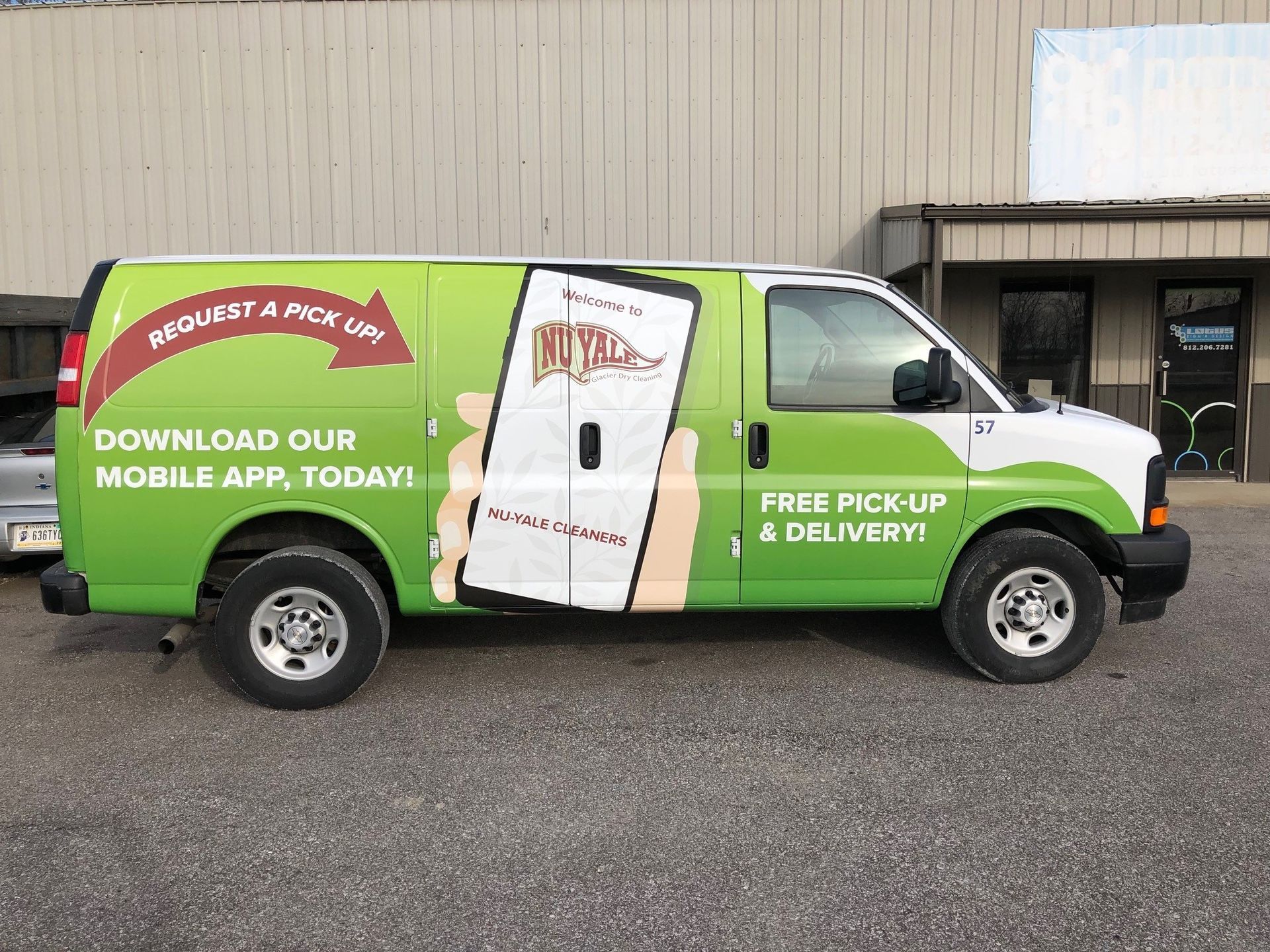 A green van is parked in front of a building.