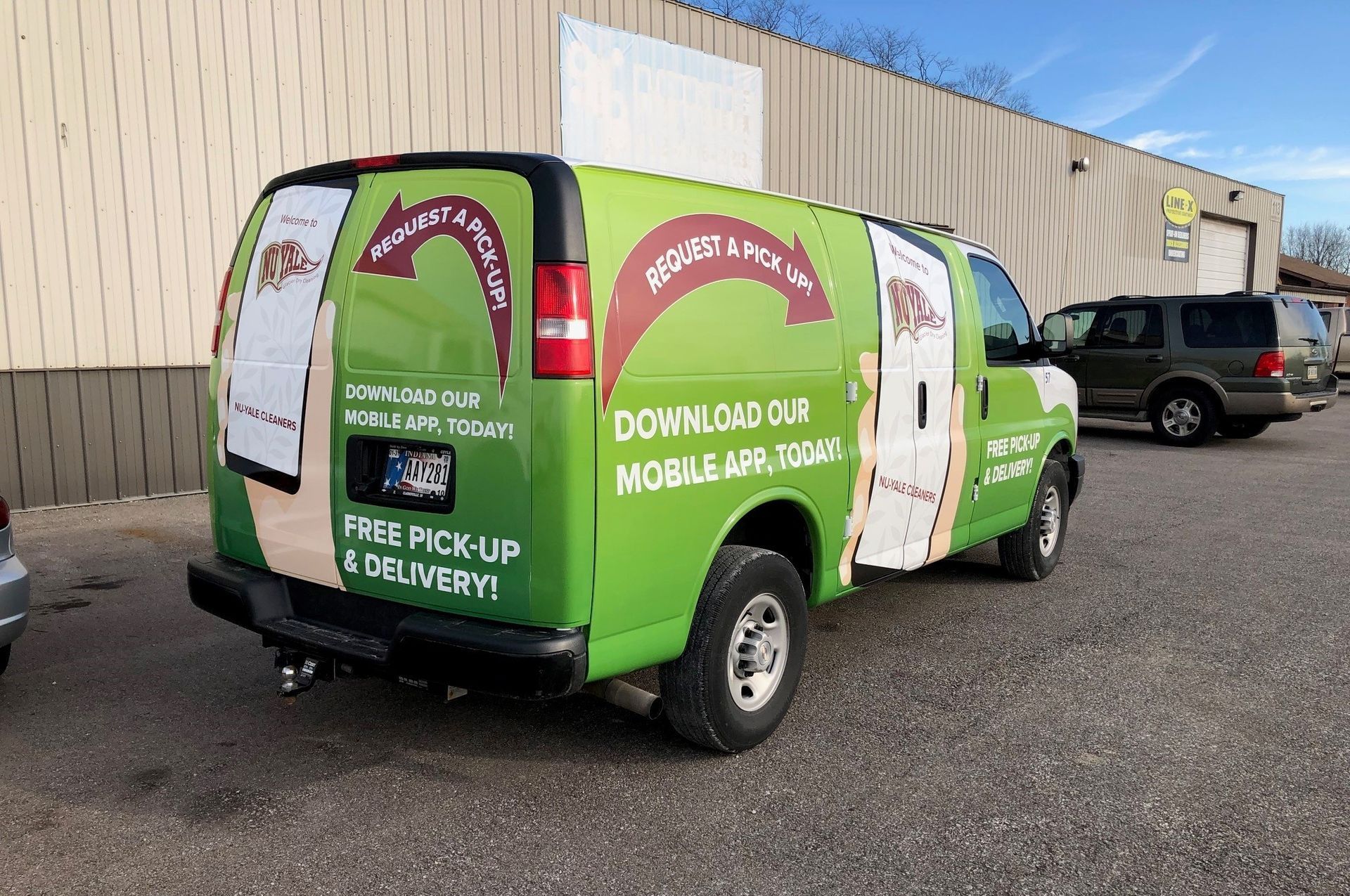 A green van is parked in front of a building.
