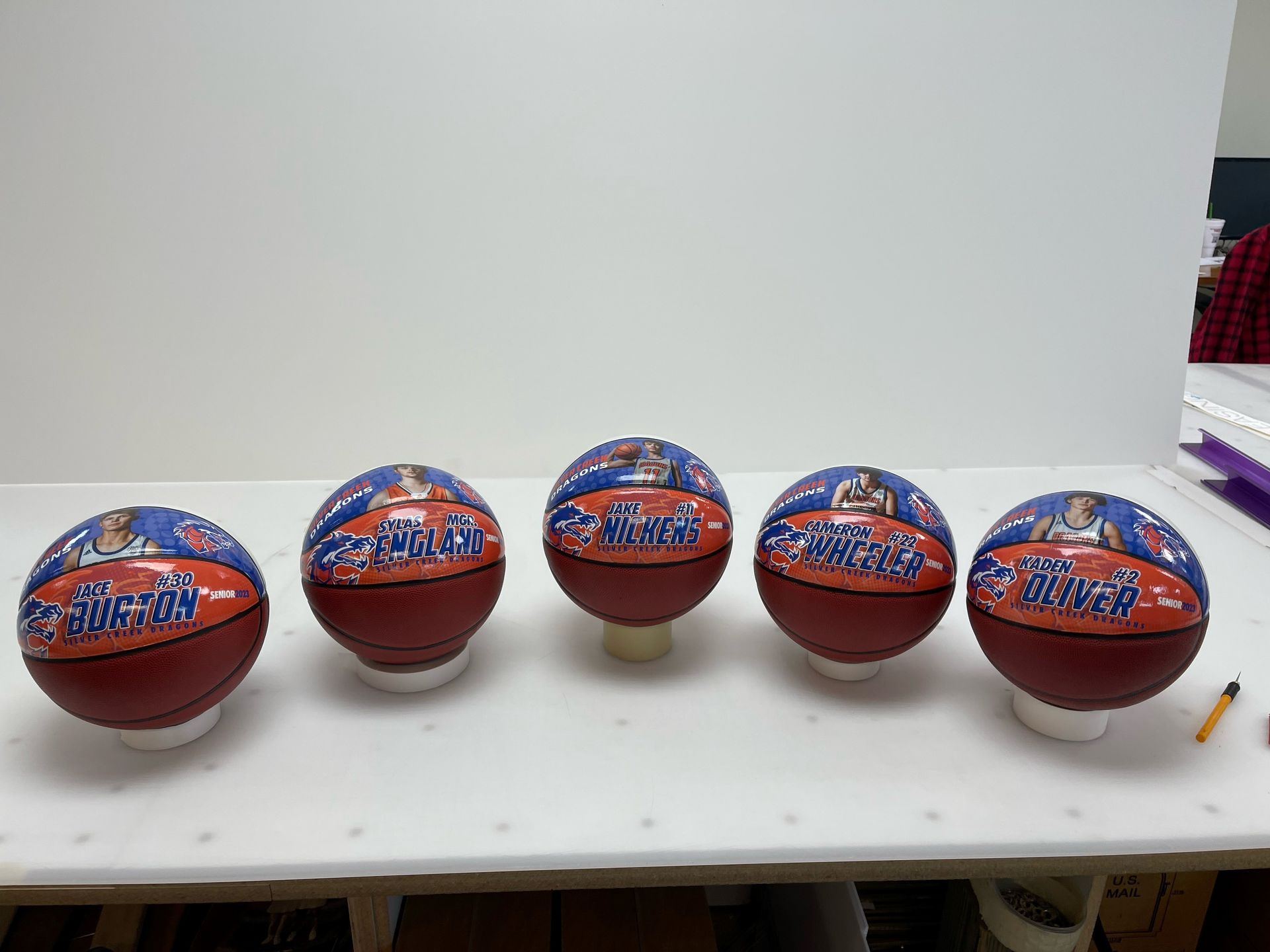Five basketballs are sitting on top of a white table.