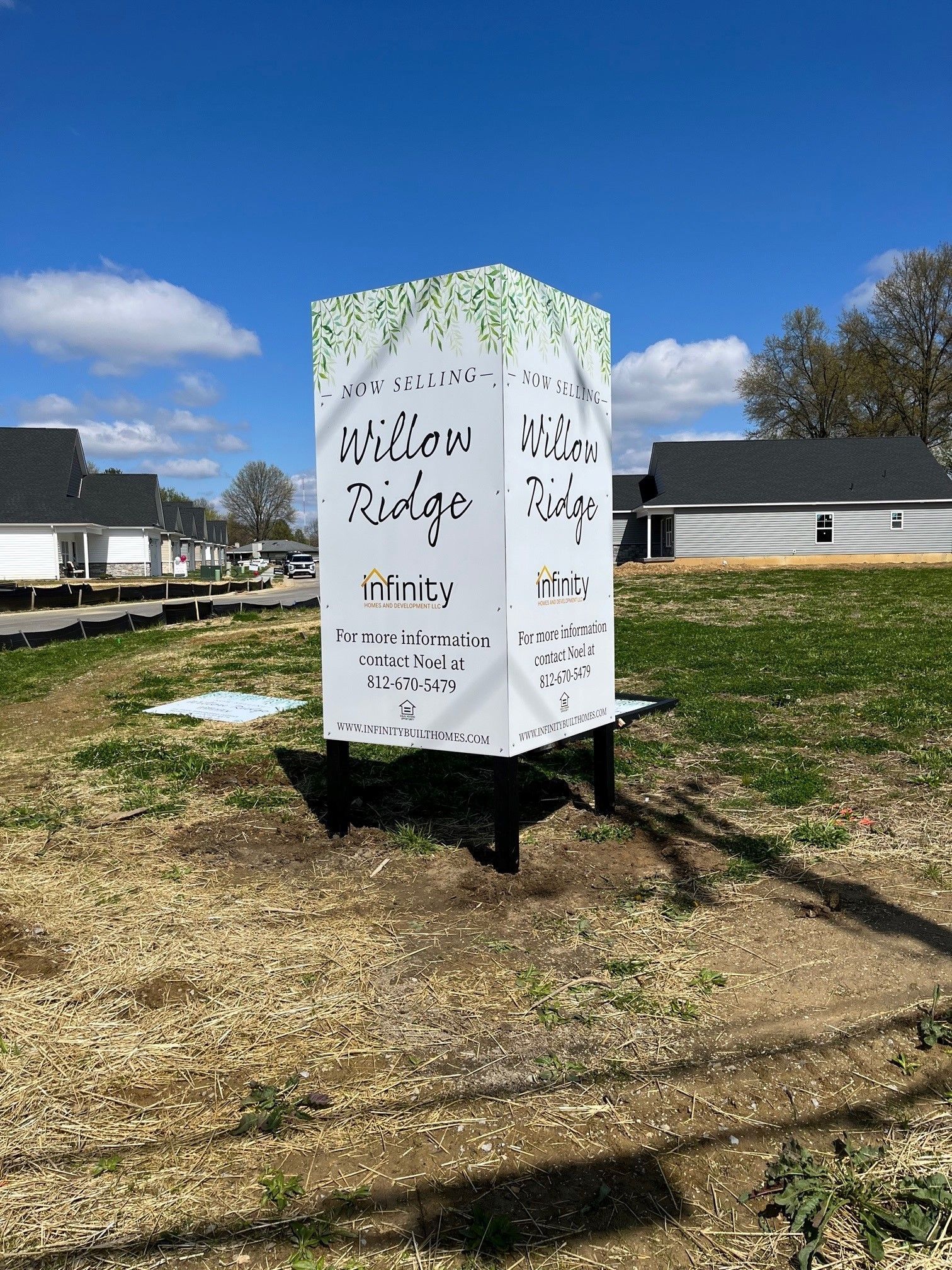A large white sign is sitting in the middle of a grassy field.