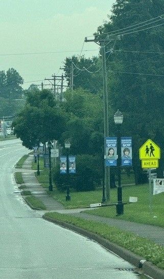 A street with a yellow school crossing sign on the side of it.