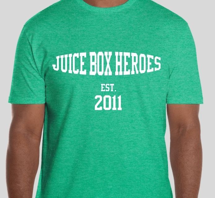 A man is wearing a green shirt that says juice box heroes