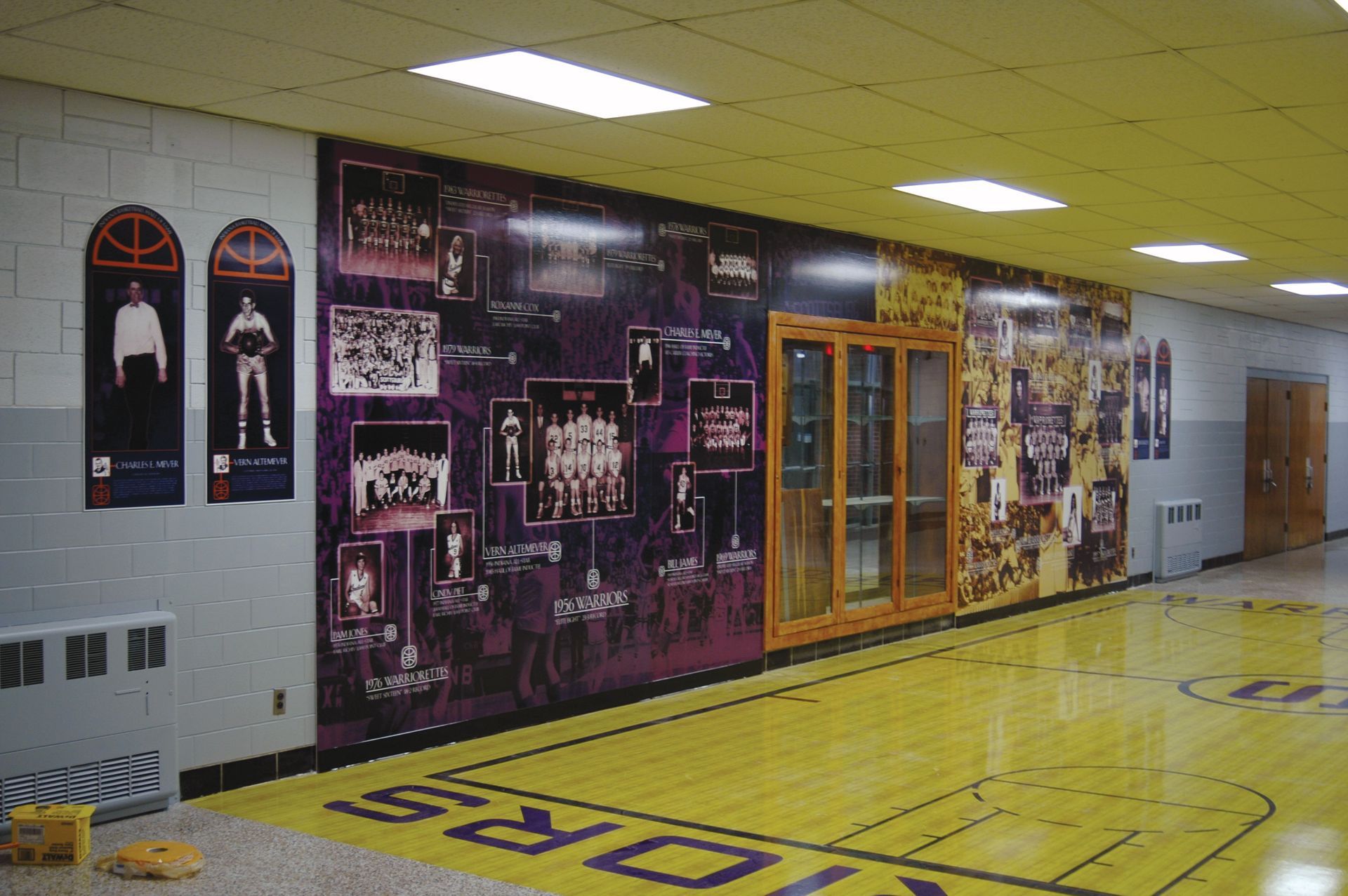 A hallway with a basketball court and a mural on the wall