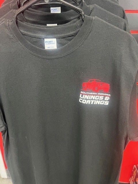 A black t-shirt is hanging on a hanger in a store.