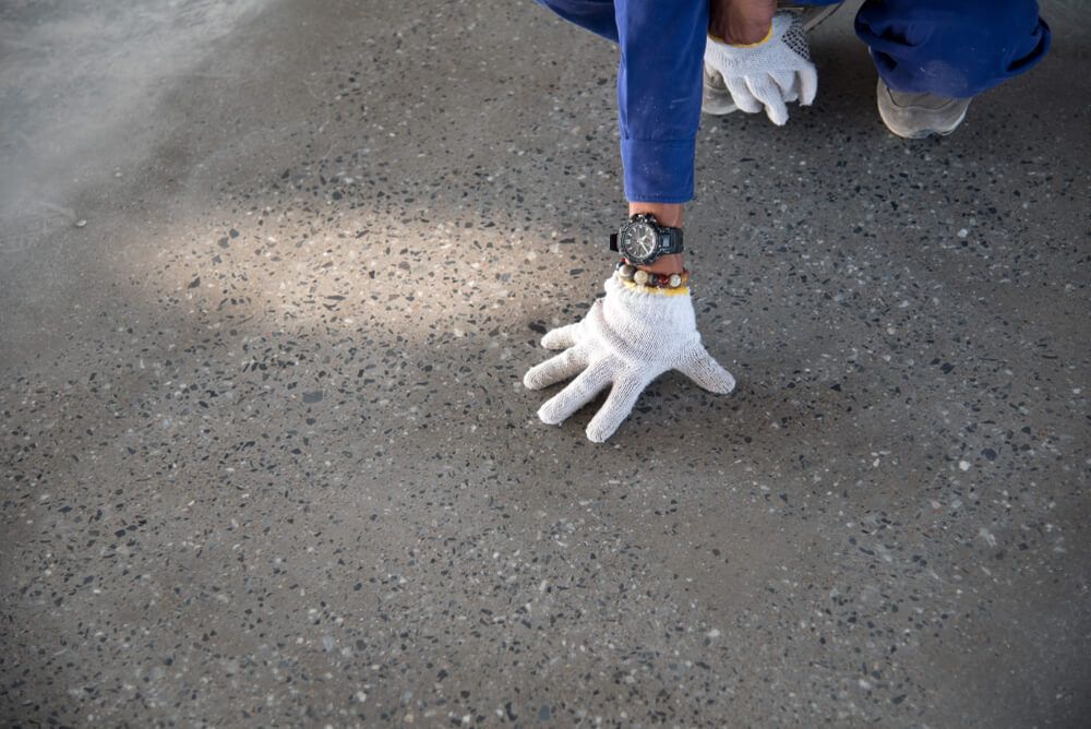 A Person Wearing White Gloves is Kneeling on the Ground — C R Concreting in Millmerran, QLD