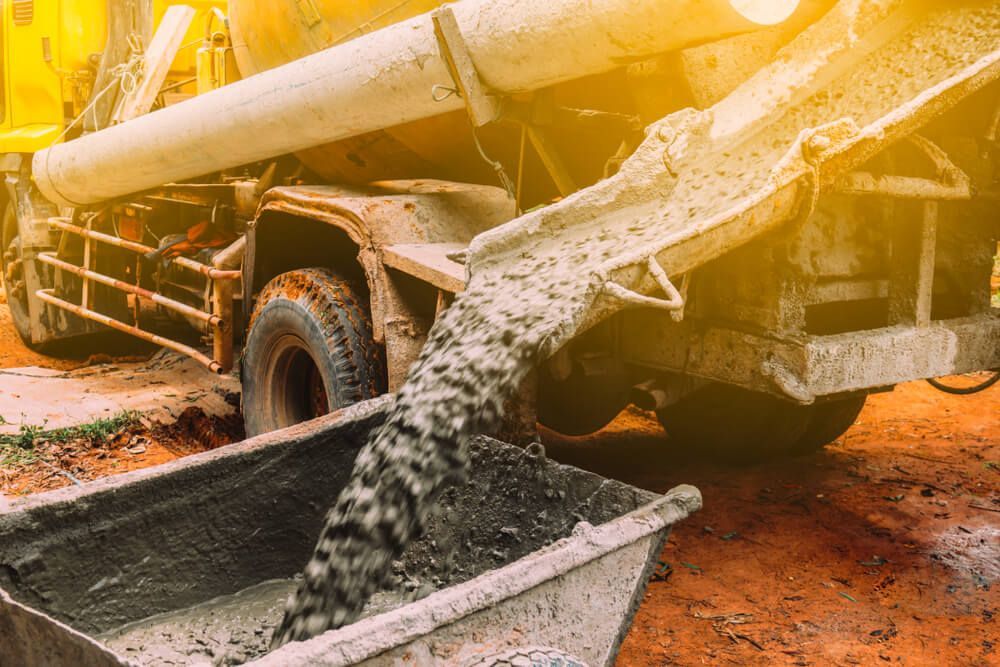 A Concrete Truck is Pouring Concrete Into a Bucket — C R Concreting in Cecil Plains, QLD