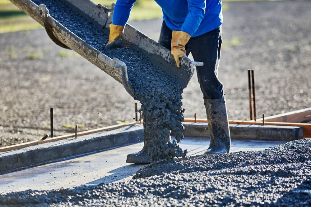 A Man is Pouring Concrete Into a Concrete Driveway — C R Concreting in Oakey, QLD