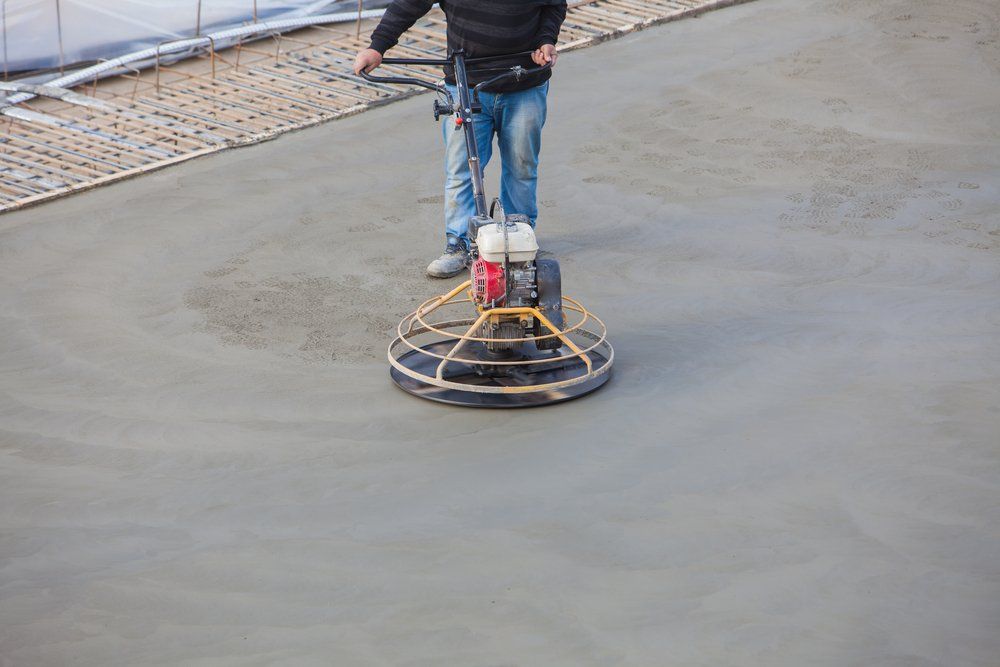 A Man is Using a Machine to Finish Concrete on a Construction Site — C R Concreting in Wyreema, QLD