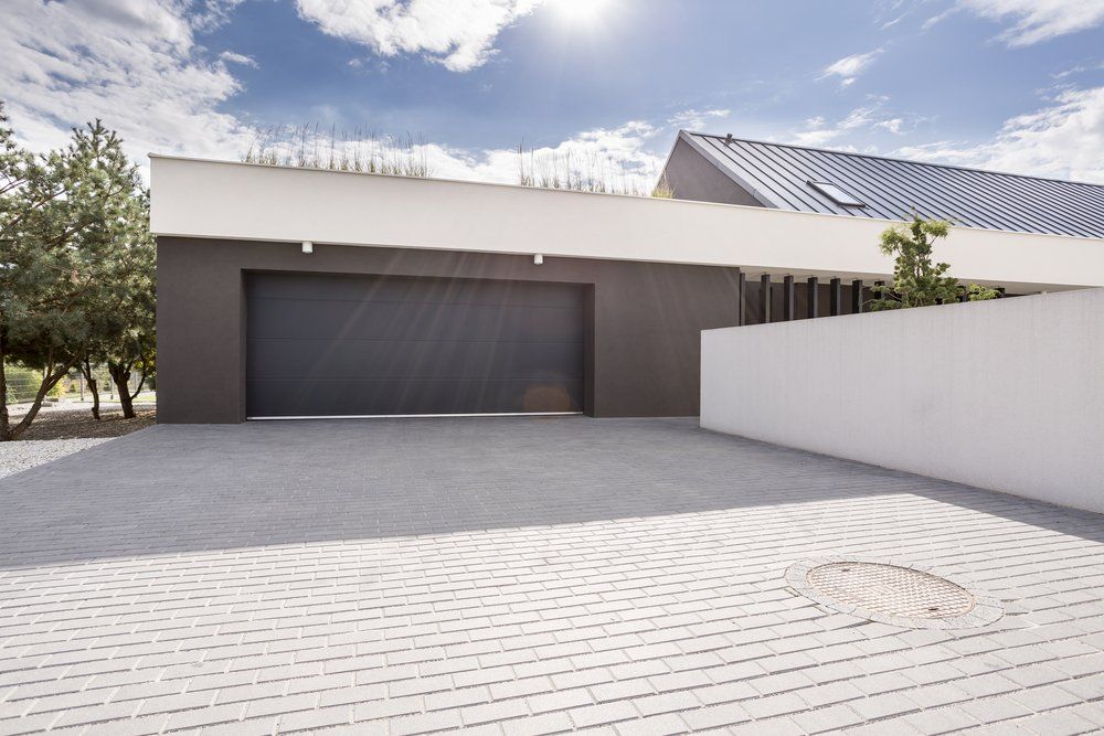 A Modern House With a Large Garage Door and a Driveway — C R Concreting in Warwick, QLD