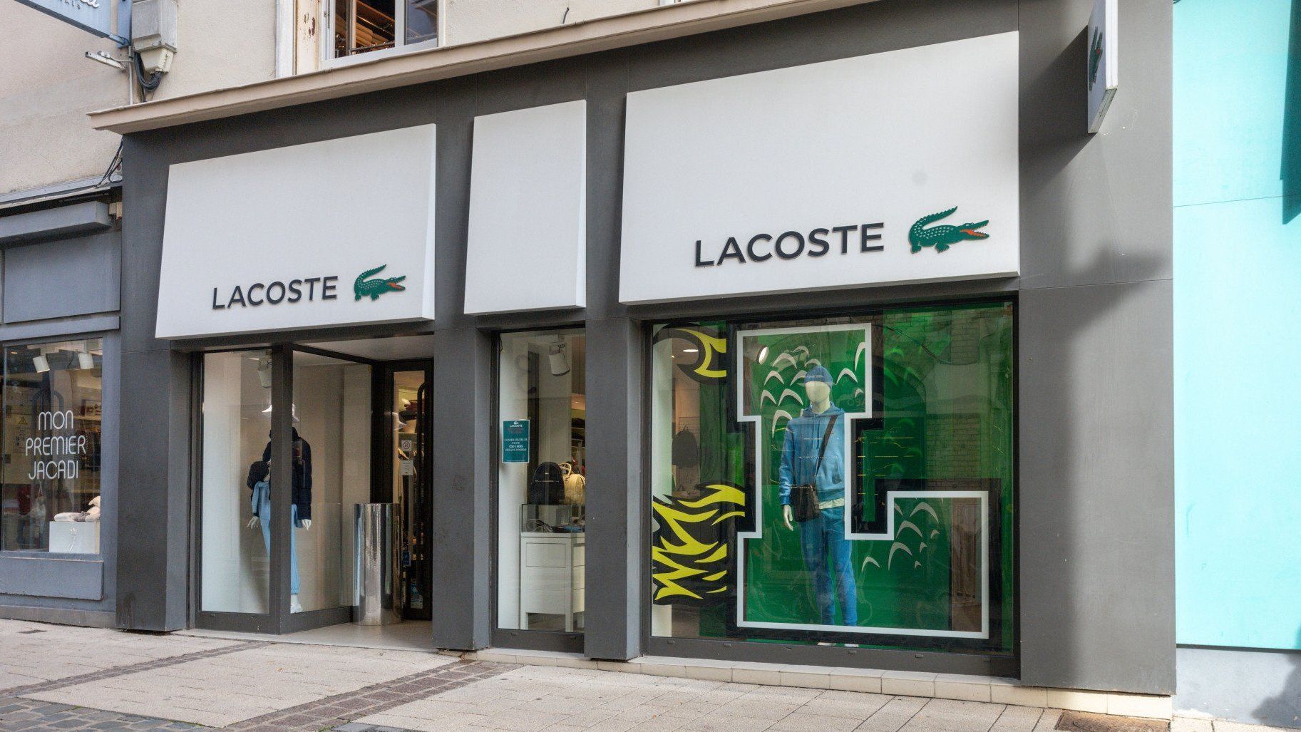 La devanture d'un magasin lacoste avec un grand l sur la vitrine.