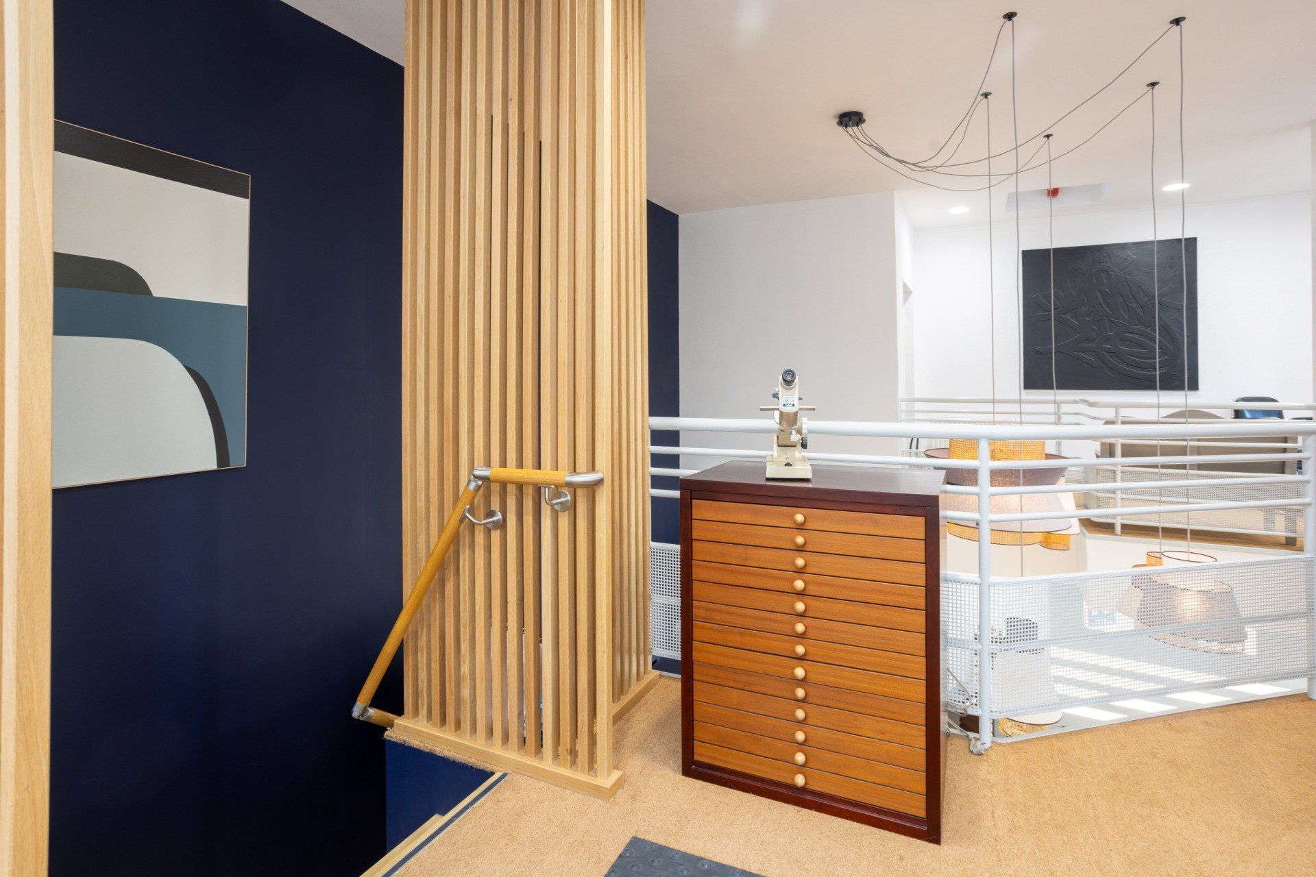 Une commode en bois se trouve dans une pièce à côté d'un escalier.