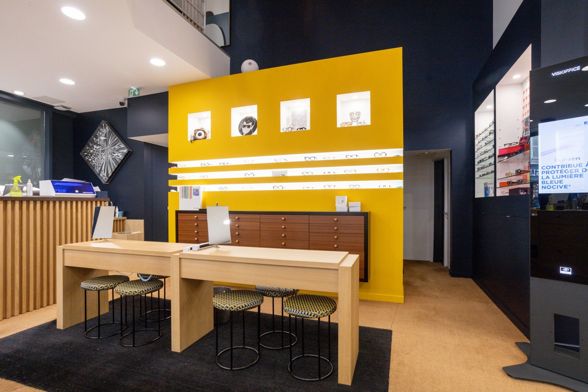 Une pièce avec un mur jaune et des tables et des chaises en bois.