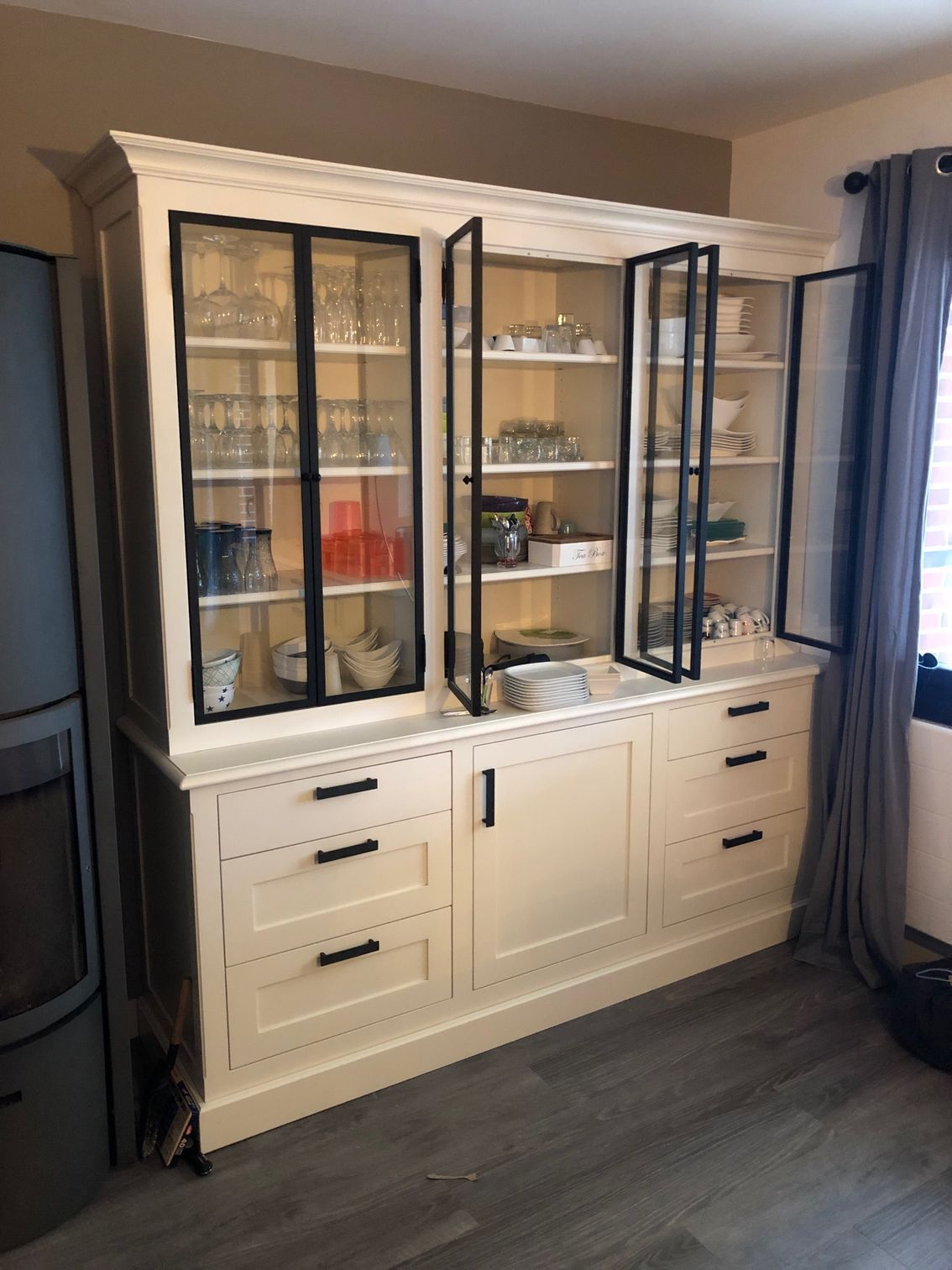 Une grande armoire blanche avec portes vitrées et tiroirs dans un salon.