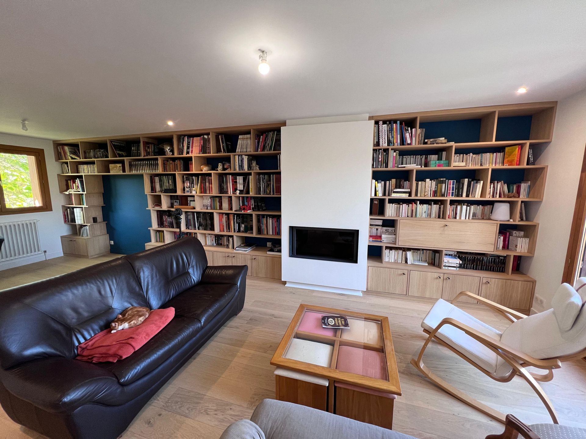 Un salon avec un canapé, une chaise, une table basse et une bibliothèque.