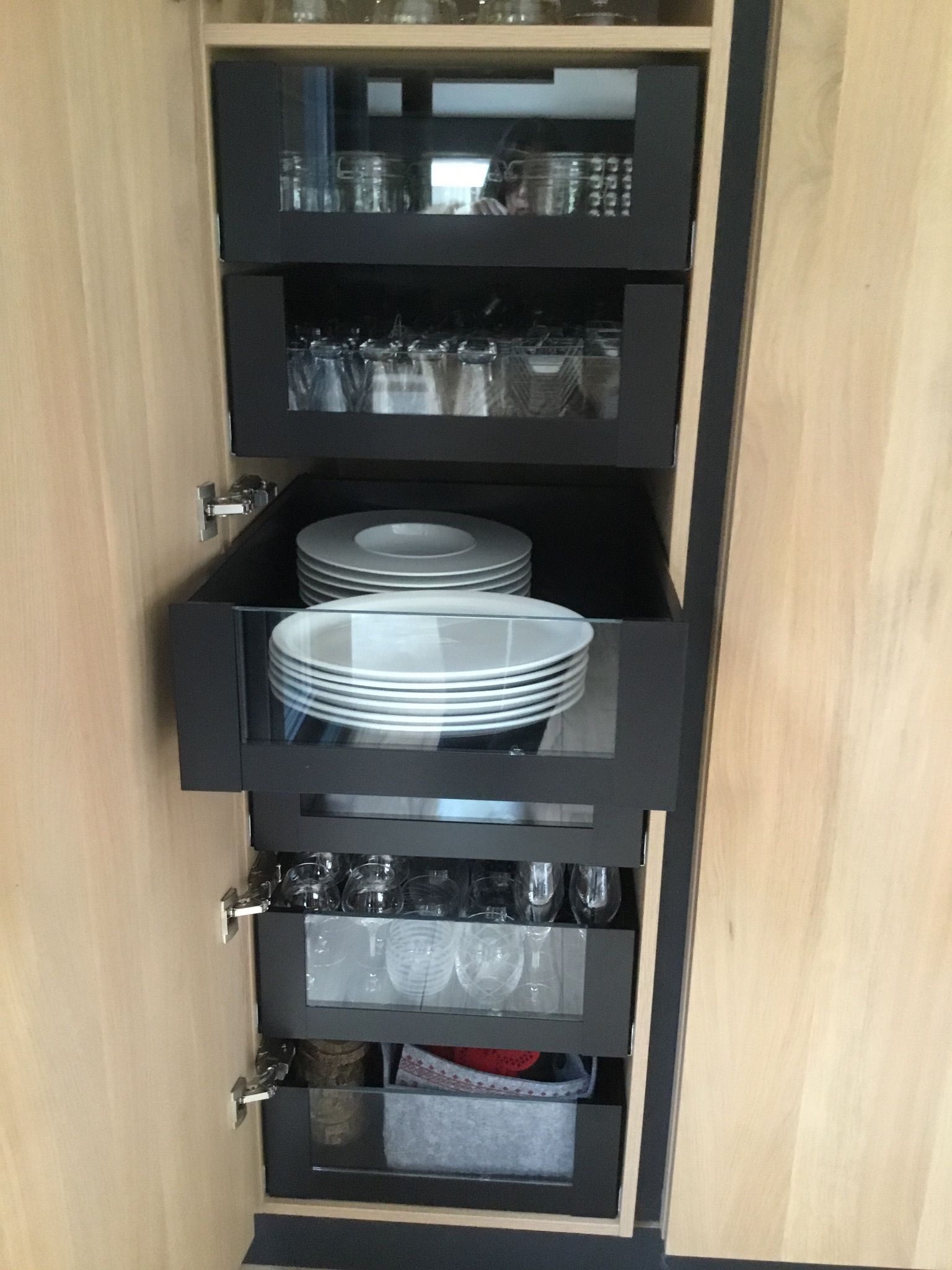 Une armoire en bois avec des tiroirs remplis d'assiettes et de verres