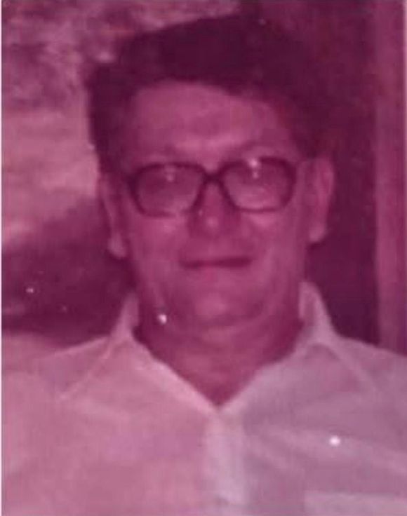 Man with glasses in a light-colored button-down shirt, looking at the camera.