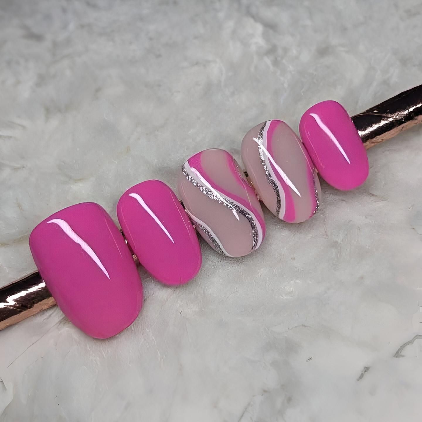 Un primer plano de una fila de uñas rosas sobre una superficie blanca.