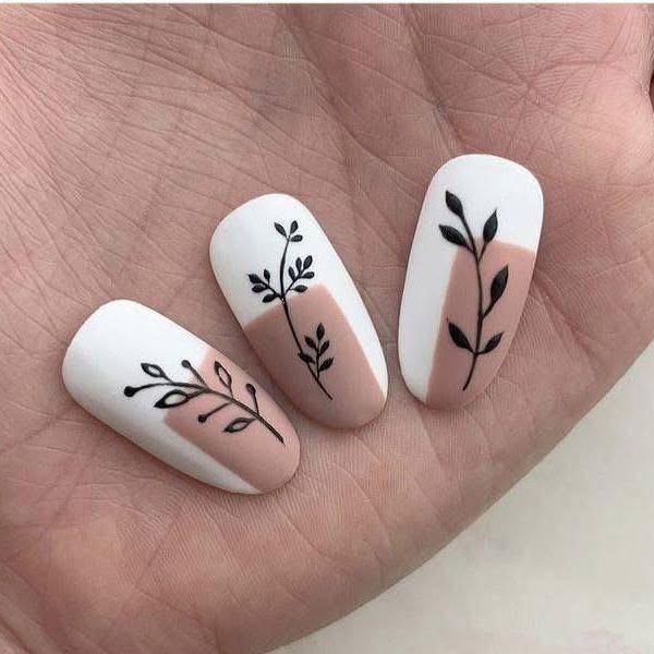 Una mano sostiene tres clavos con hojas en ellos.
