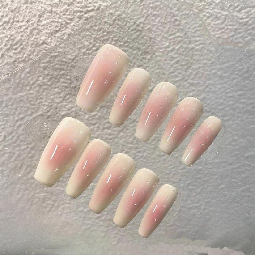 Un primer plano de un conjunto de uñas rosas y blancas sobre una mesa.