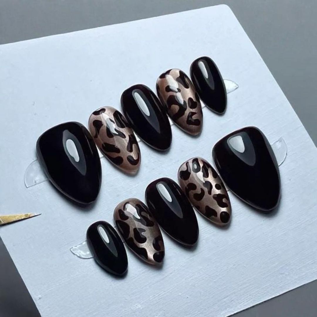 Un juego de uñas negras con estampado de leopardo.