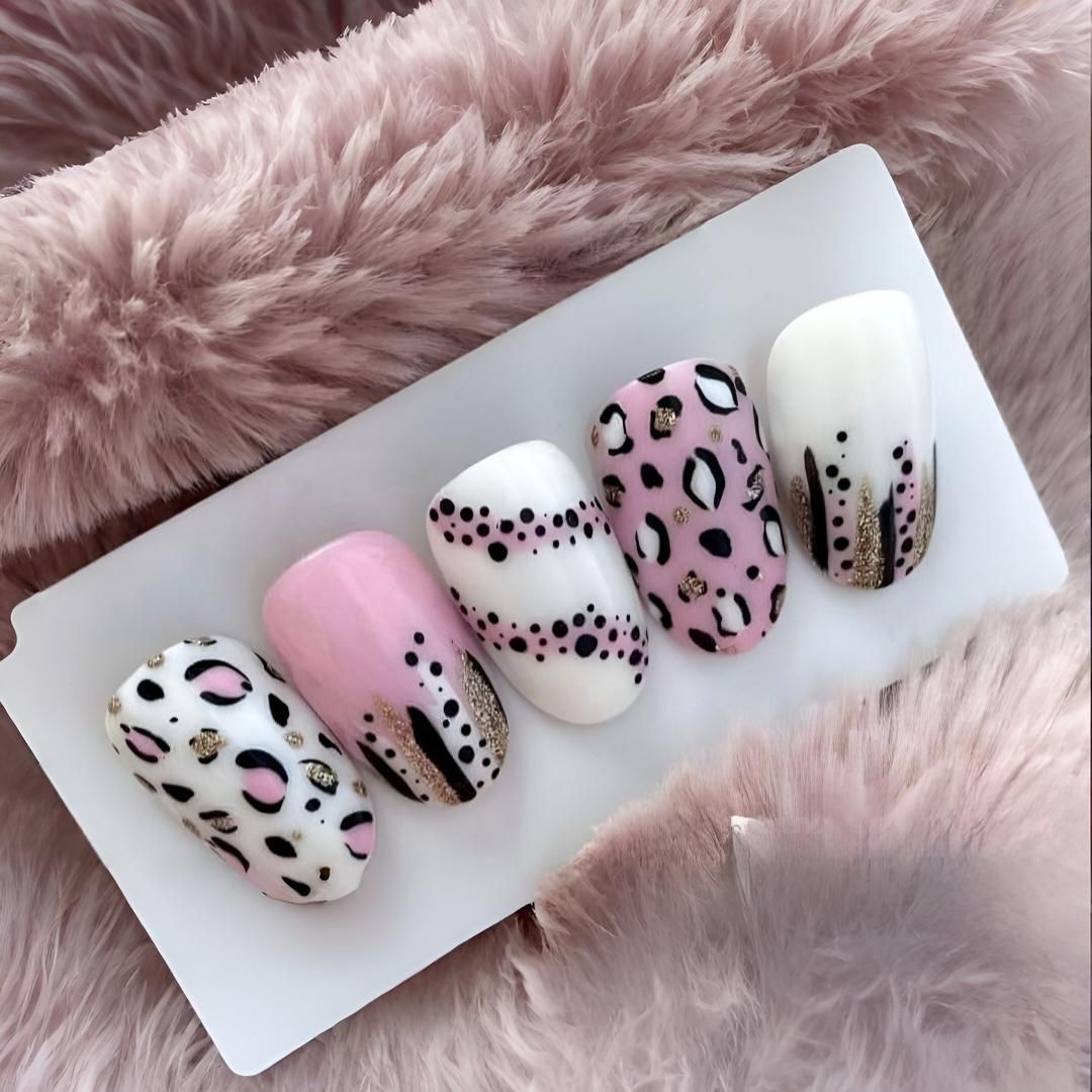Un conjunto de uñas rosas y blancas con un diseño de estampado de leopardo.