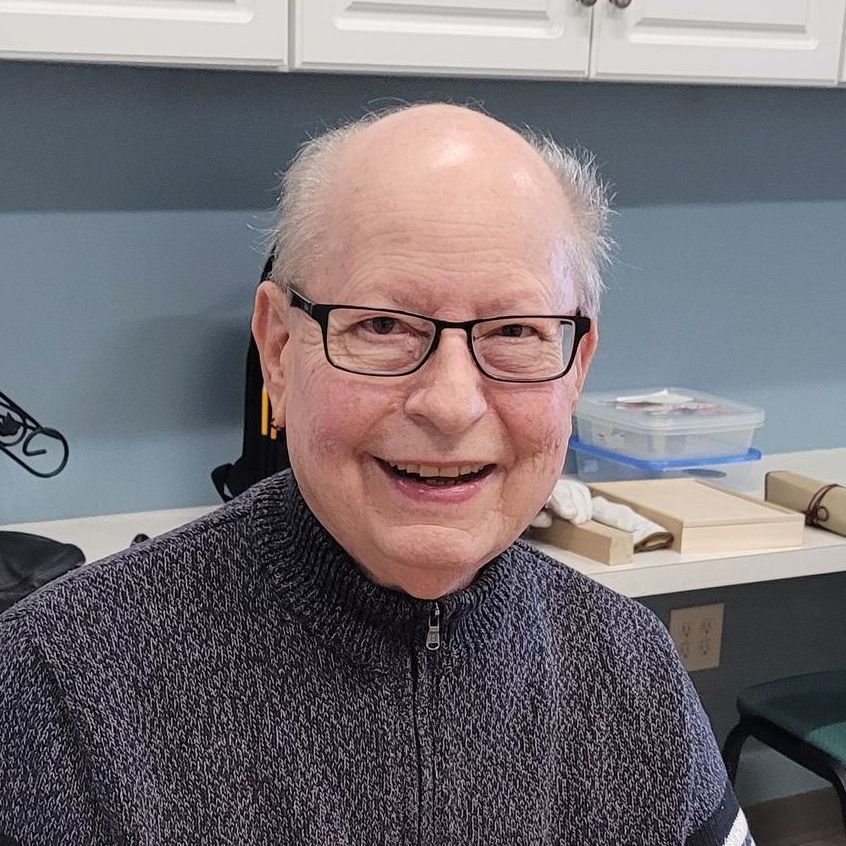 A woman is leaning against a tree while holding a yoga mat and a cell phone.