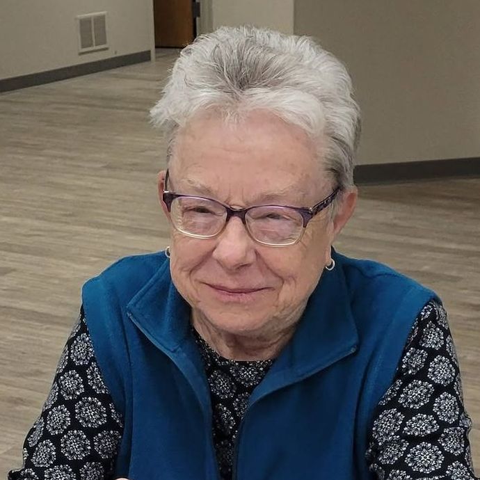 A group of people are sitting around a table talking to each other.