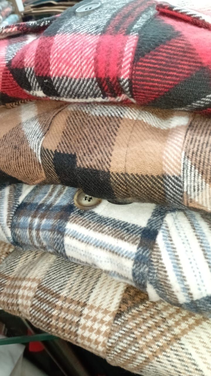 Una pila de camisas a cuadros están colocadas una encima de otra sobre una mesa.