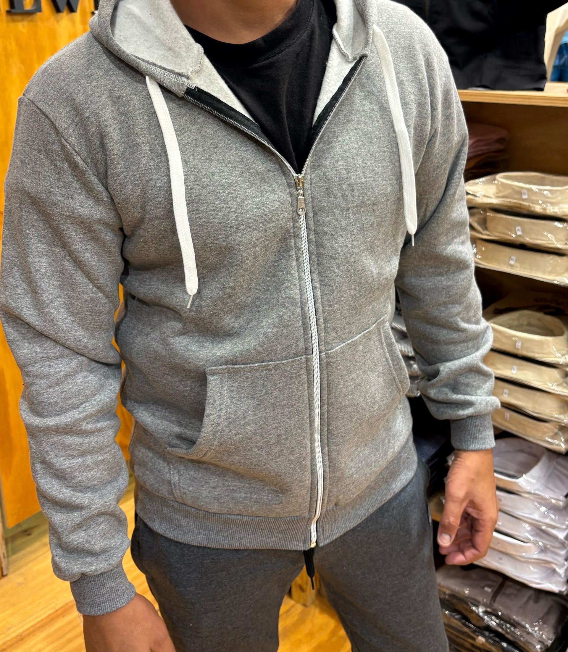 Un hombre que lleva una sudadera con capucha gris está parado en una tienda.