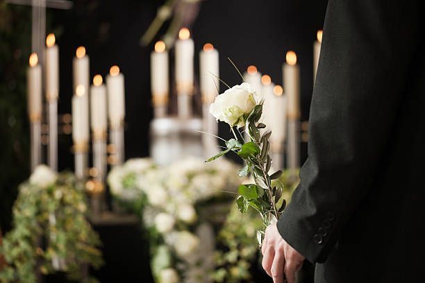 Person holding a white rose at a candlelit funeral service