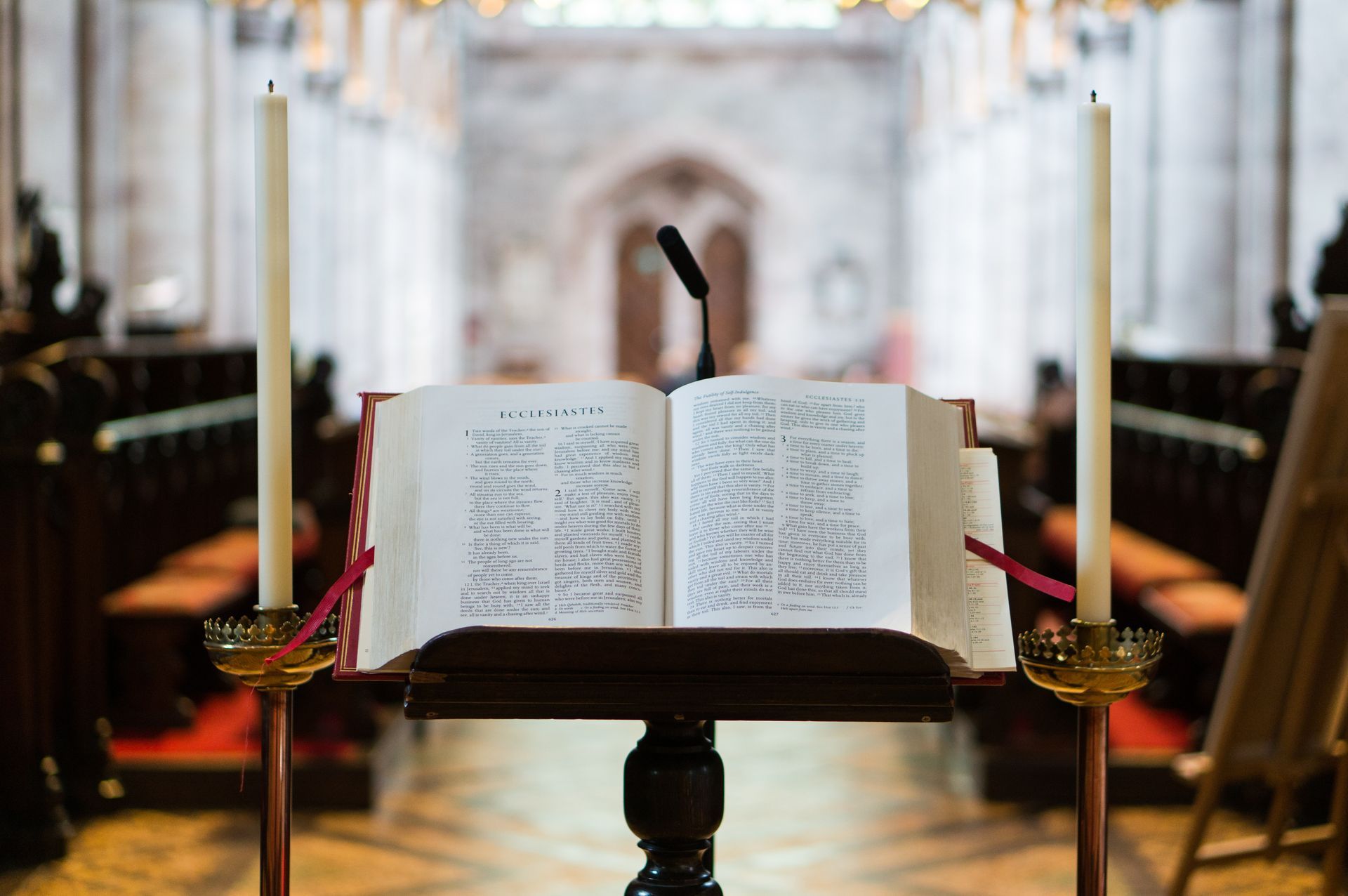 Open Bible on a stand in a church with candles on either side
