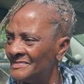 Close-up of a smiling woman with short gray hair outdoors in bright sunlight