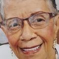 Close-up of a smiling person wearing glasses, with a warm-toned background