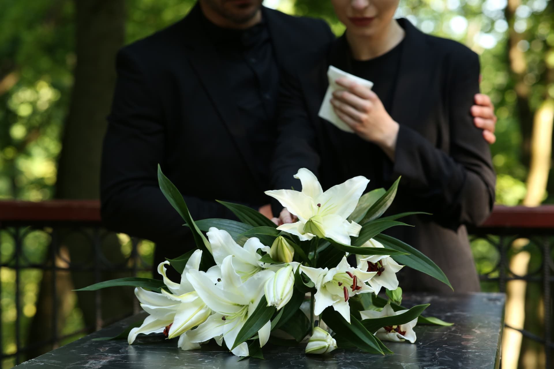 People in the background of a funeral service with white flowers..